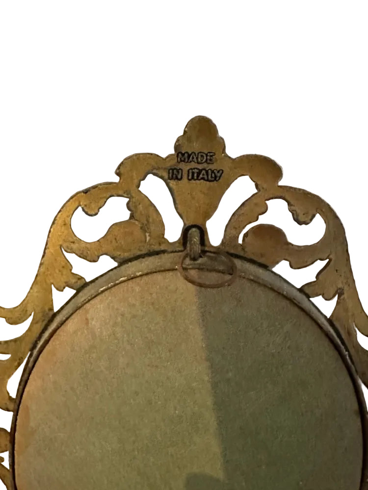 Close-up of plaque's gilt frame crest with 'Made in Italy' stamp and wire hanging loop