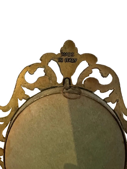 Close-up of plaque's gilt frame crest with 'Made in Italy' stamp and wire hanging loop