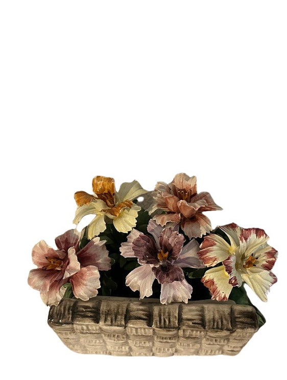 Close-up front view of peach, pink and yellow Capodimonte porcelain blooms in a woven basket