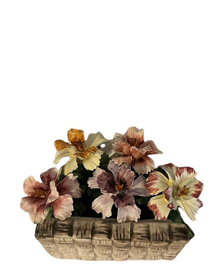 Close-up front view of peach, pink and yellow Capodimonte porcelain blooms in a woven basket