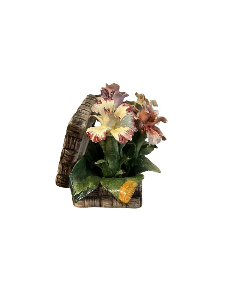 Angled view of Capodimonte porcelain lilies rising from a woven ceramic basket