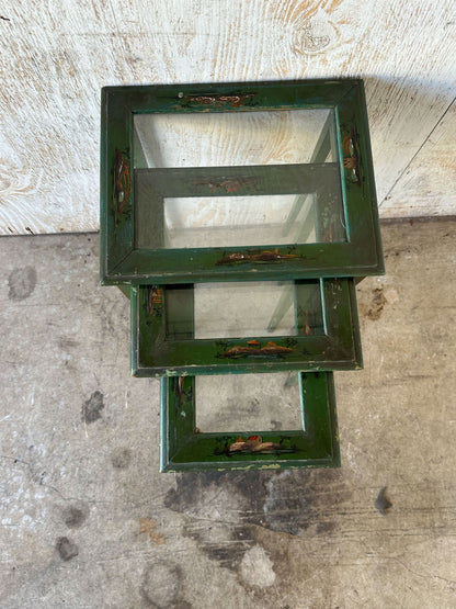 Top view of stacked green lacquered nesting tables showing graduated open frames
