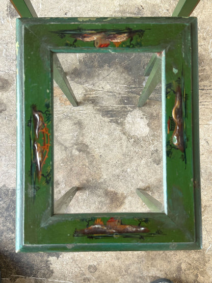 Top-down view of green lacquered nesting table frame with hand-painted corner scenes