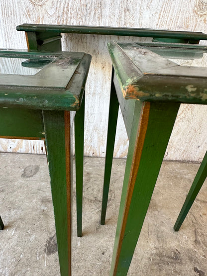 Close-up of green lacquered nesting table legs and tops against weathered wood backdrop