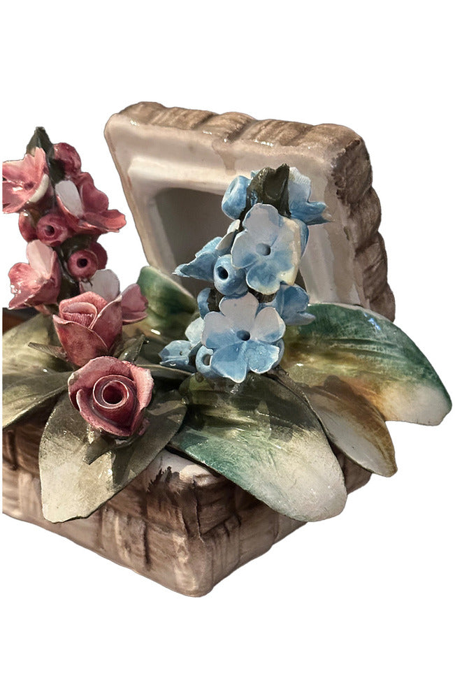 Capodimonte porcelain arrangement, angled overhead close-up of pink roses and blue blossoms in a woven basket