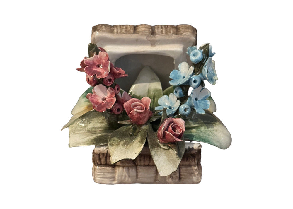 Capodimonte porcelain floral basket, front view, clustered pink roses and blue flowers above a woven base