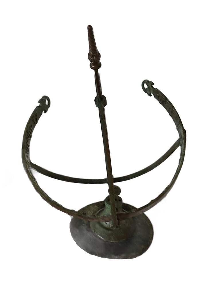 Top-down view of the bronze armillary rings and the central arrow gnomon, green verdigris patina