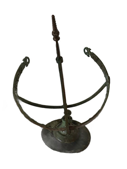 Top-down view of the bronze armillary rings and the central arrow gnomon, green verdigris patina