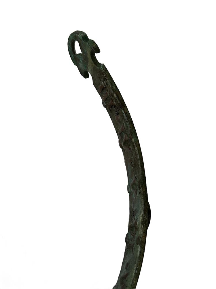 Detail of one curved verdigris bronze arm of the sundial ending in a decorative scroll terminal