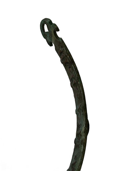 Detail of one curved verdigris bronze arm of the sundial ending in a decorative scroll terminal