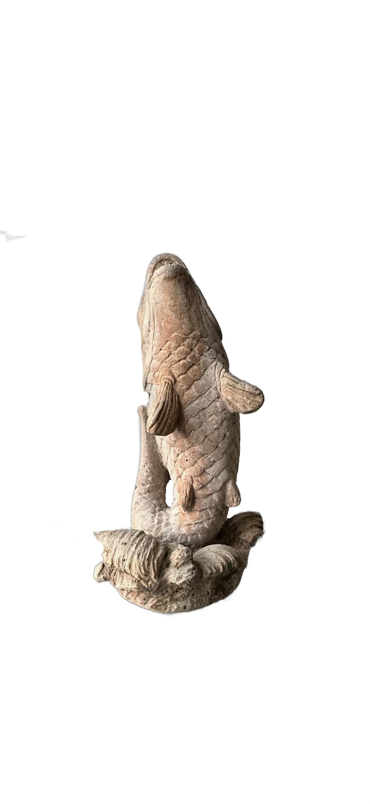 Vintage concrete koi fountainhead seen from behind, showing the carp's body and fins