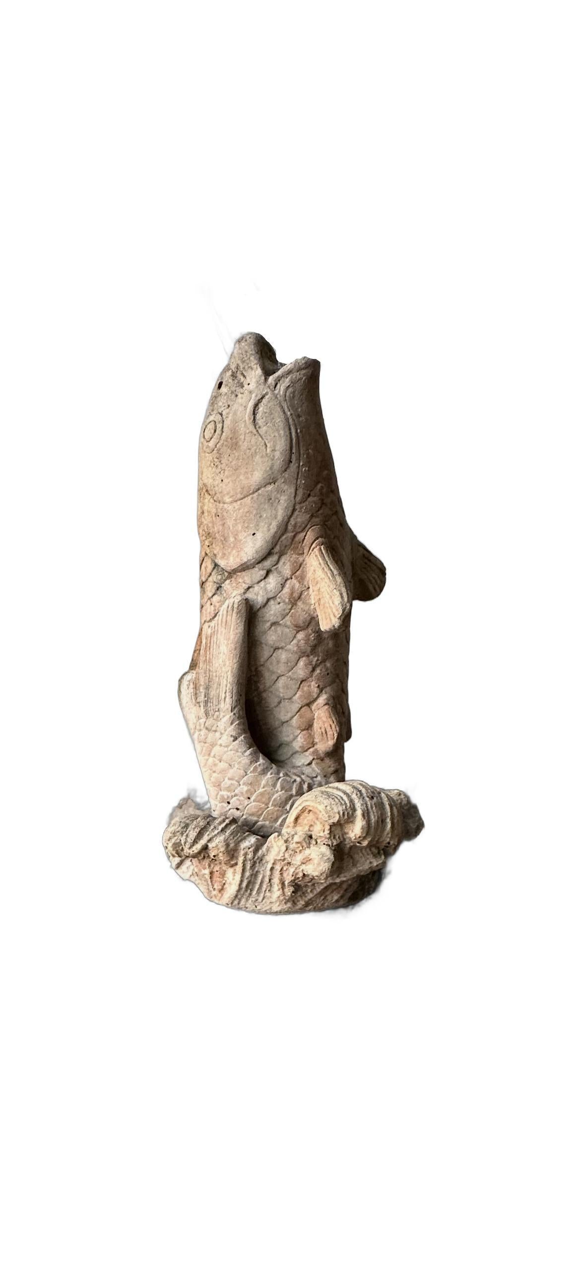 Vintage concrete koi fountainhead, carp leaping upright from a wave base, weathered front view
