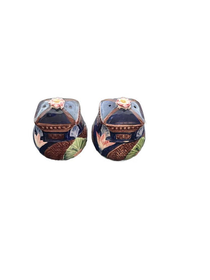Angled view of ceramic basket salt and pepper shakers with floral finials and fan motif