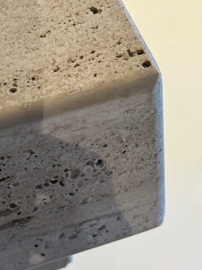 Close-up of the top corner of a travertine pedestal showing pitting and veining.