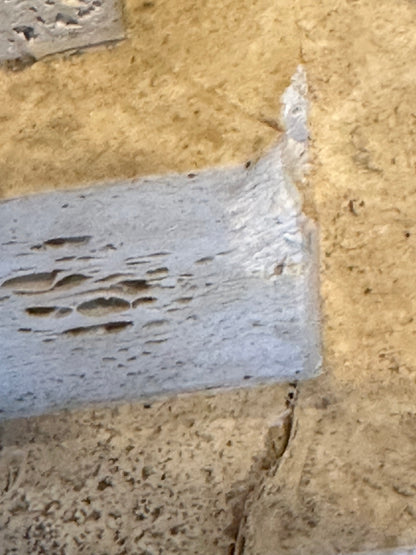 Close-up of a chipped edge with filler on a limestone pedestal base.