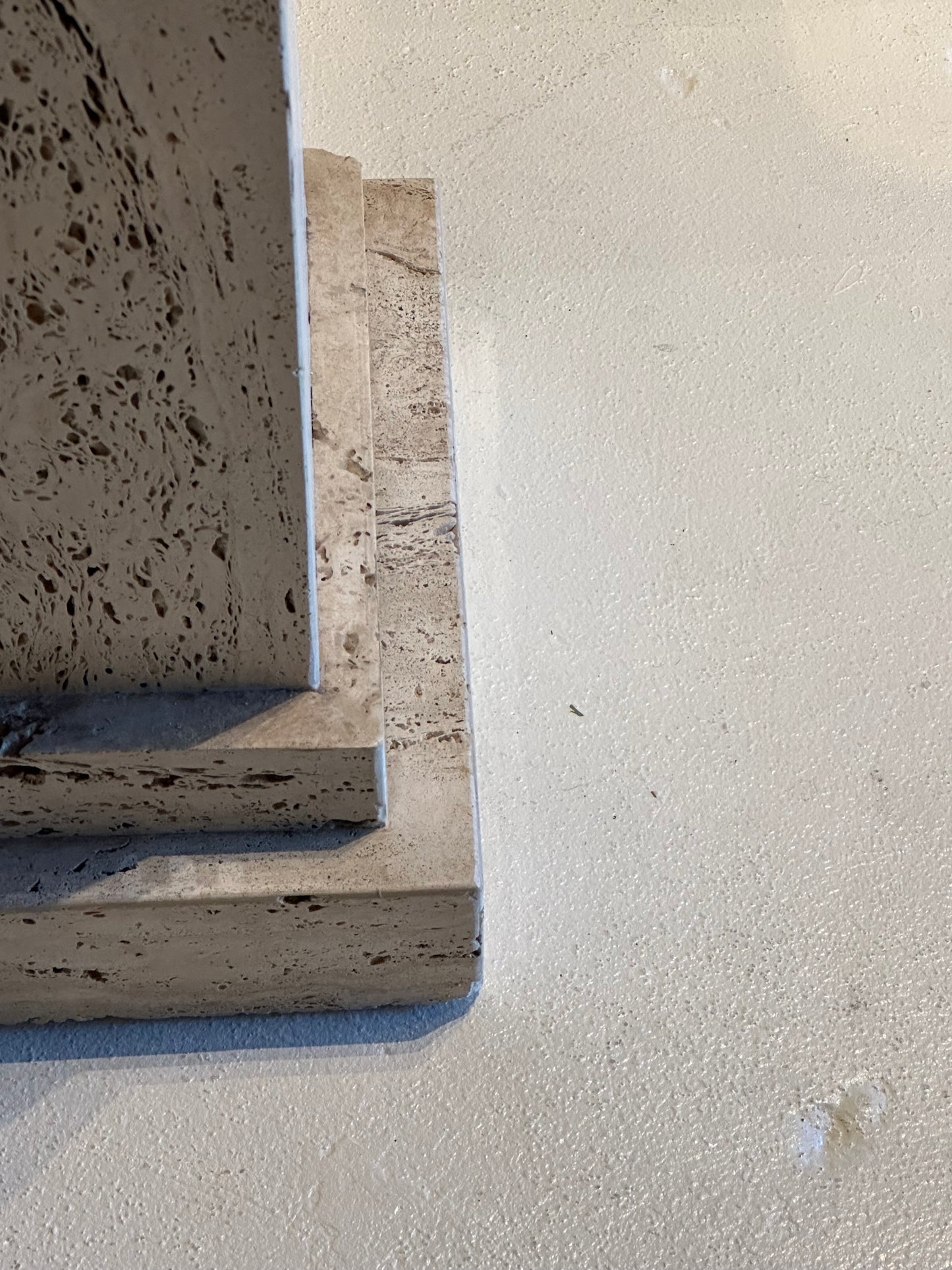 Close-up of the stepped base and pitted travertine surface of a limestone pedestal.