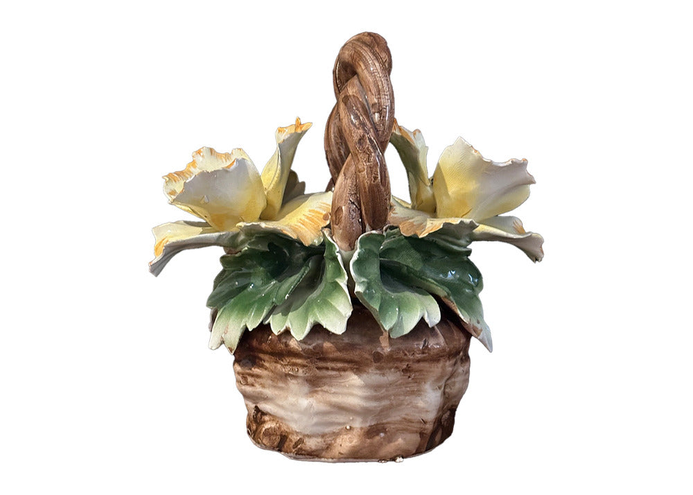 Capodimonte porcelain flower basket, front view: yellow blossoms, green leaves and a woven brown handle.