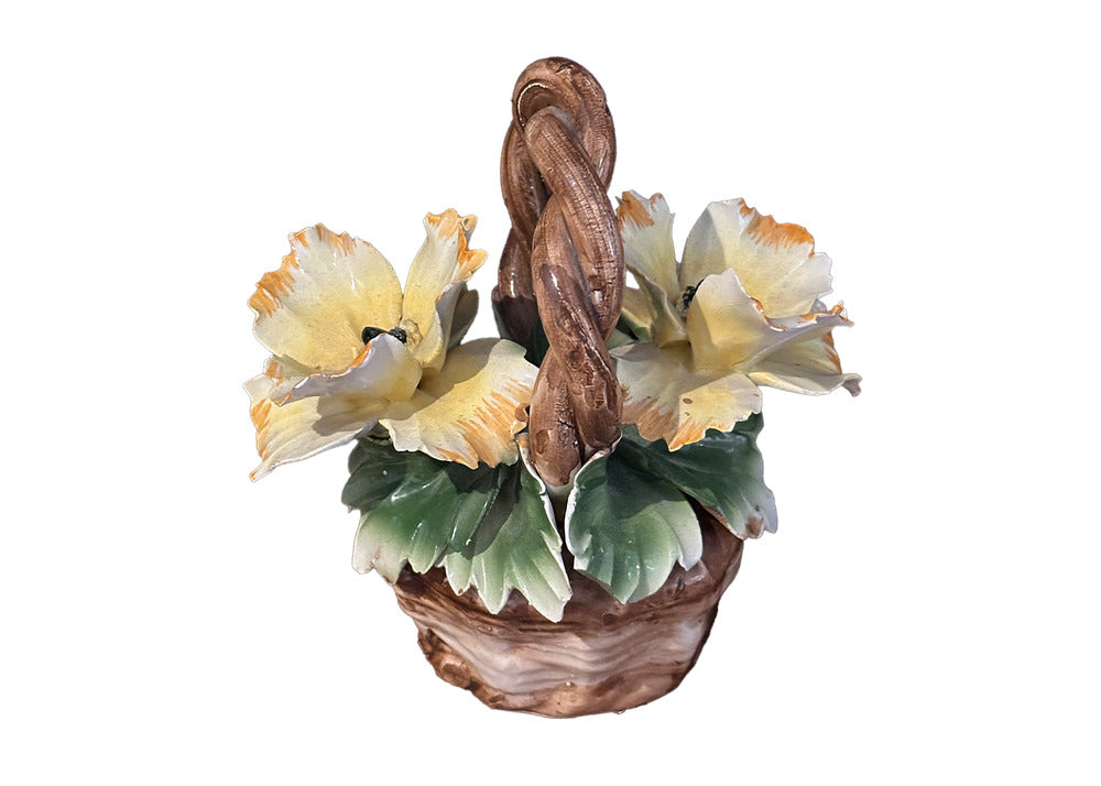 Capodimonte porcelain basket, angled view of two yellow ruffled blossoms and green leaves.