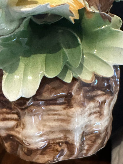 Close-up of the Capodimonte basket base: glossy green porcelain leaves over a brown woven weave.