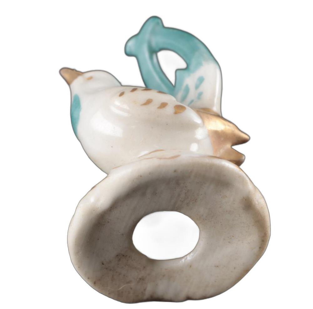 Close-up of a place card holder, turquoise tail loop above the ring-shaped card slot of the base