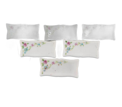 Six pillow-shaped porcelain bases, three with hand-painted pink-and-blue floral sprays and three plain