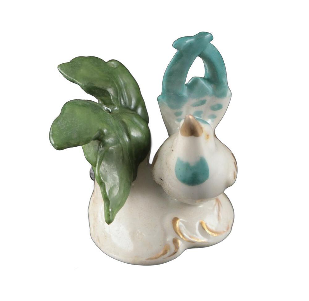 Rear view of a place card holder, back of the turquoise bird and leaf above the white card-slot base