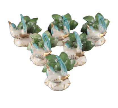 Six bird place card holders arranged in a pyramid, each a turquoise bird perched on a leaf