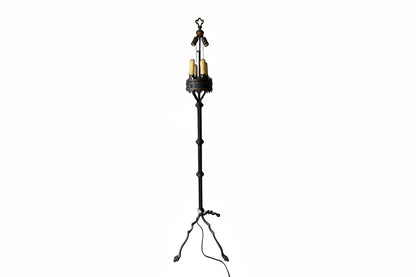 Wrought-iron floor lamp, fleur-de-lis finial over candle-style bulbs in a crown gallery, splayed tripod feet