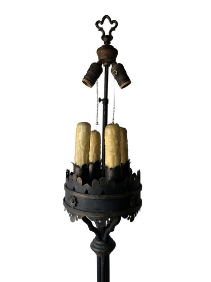Upper section of the iron floor lamp, twin sockets and faux-candle covers below a fleur-de-lis finial