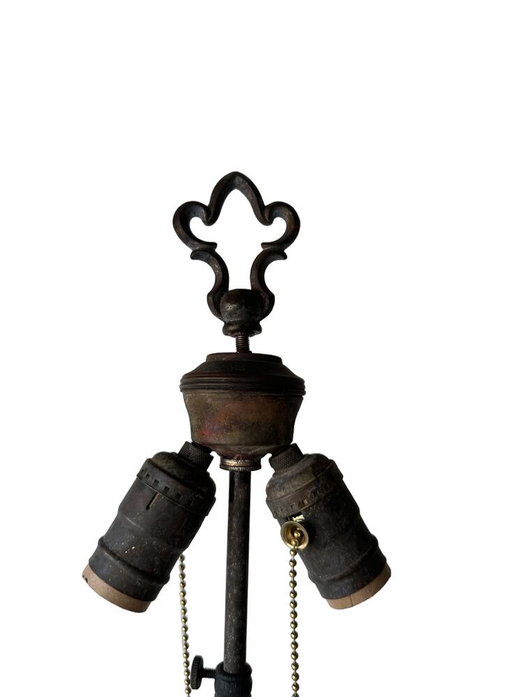 Top of the iron floor lamp, fleur-de-lis finial above two sockets with pull-chains