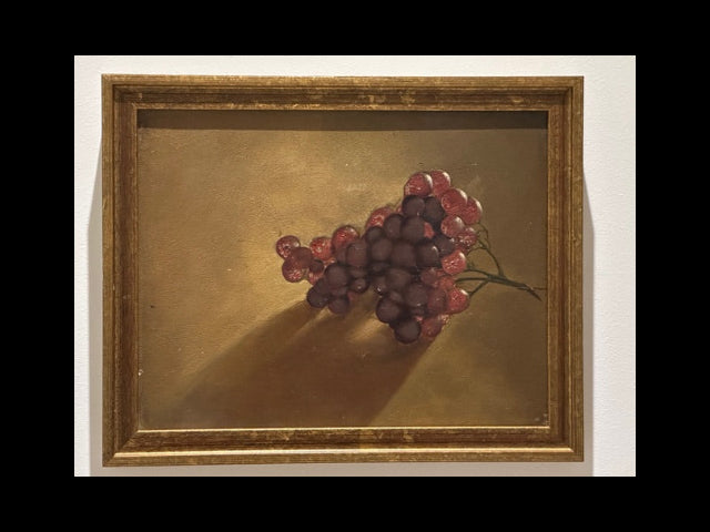 Framed grapes still life painting hanging on white wall, gilt wood frame