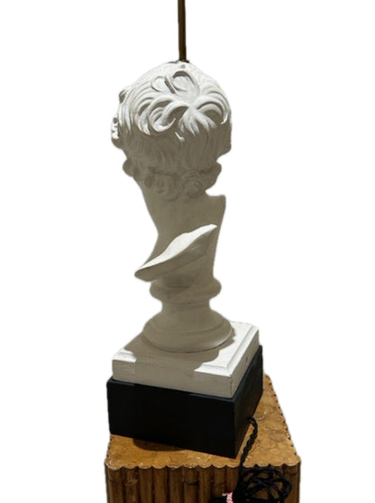 Side view of the plaster bust lamp on black plinth atop a bamboo-style wood pedestal