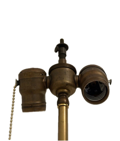 Close-up of the lamp's aged brass twin-socket cluster with pull-chain switch