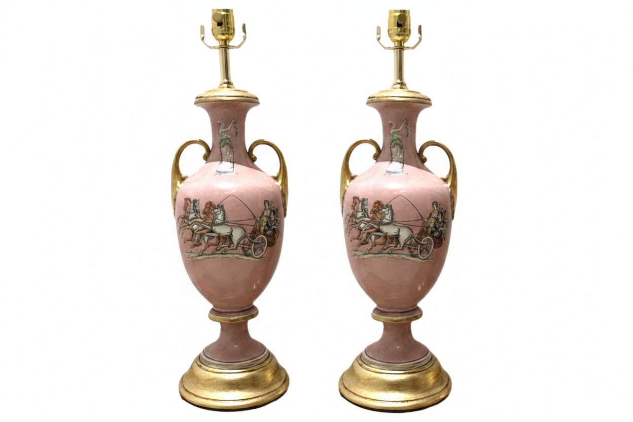 Pair of pink ceramic urn lamps with twin gold handles, chariot scenes and gilt round bases