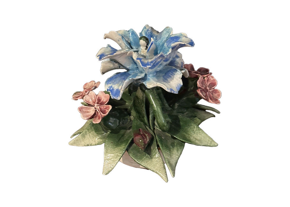 Close view of Capodimonte porcelain blooms: blue flower and pink blossoms among detailed green leaves