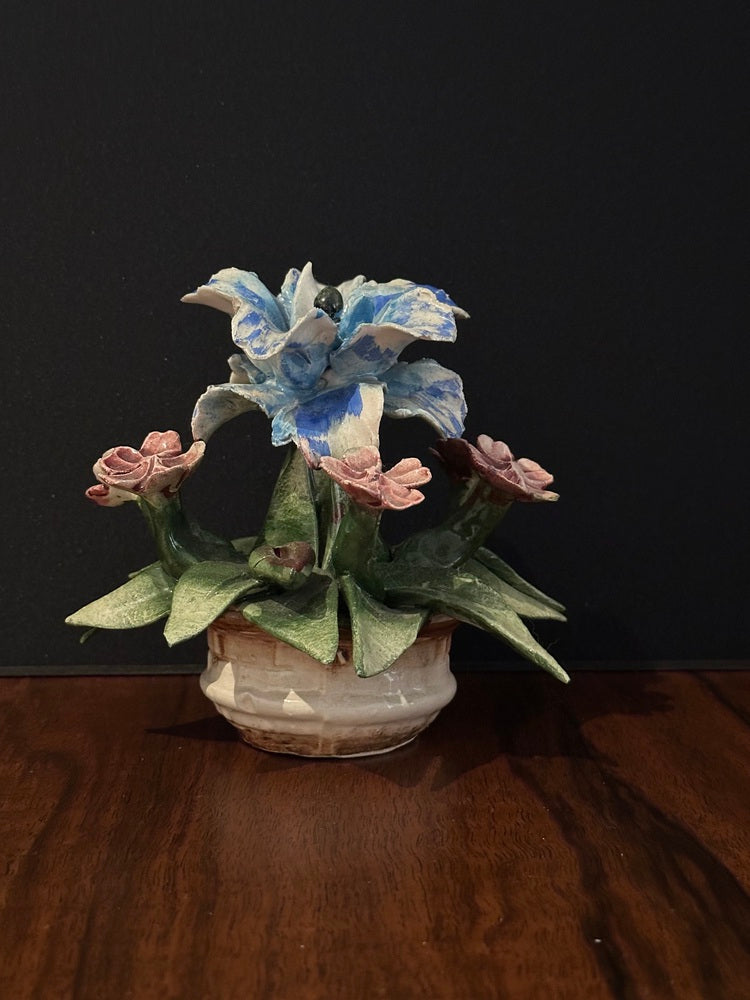 Capodimonte porcelain floral arrangement displayed on dark wood tabletop against a black background