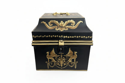 Vintage tole hinged box, front view; black metal with gilt griffins flanking an urn motif and a foliate swag on the lid