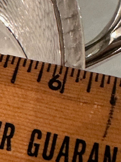 Silver-plate ice tongs measured against a wooden ruler near the six-inch mark