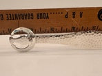 Silver-plate ice tongs laid against a wooden ruler to show their overall length