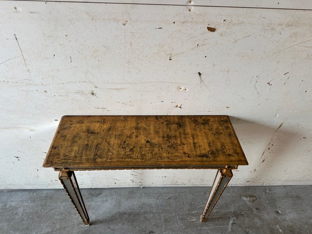 Italian pier table, front view against a distressed wall, gilt wood with mirror accents