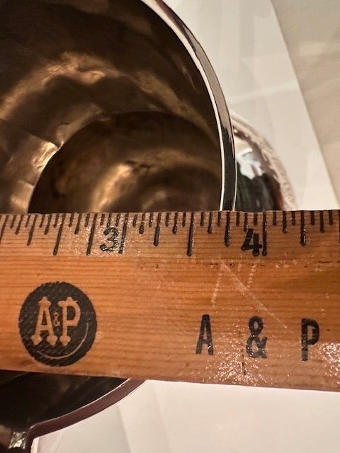 Silver pitcher base beside an A&P wooden ruler measuring width near 3 to 4 inches