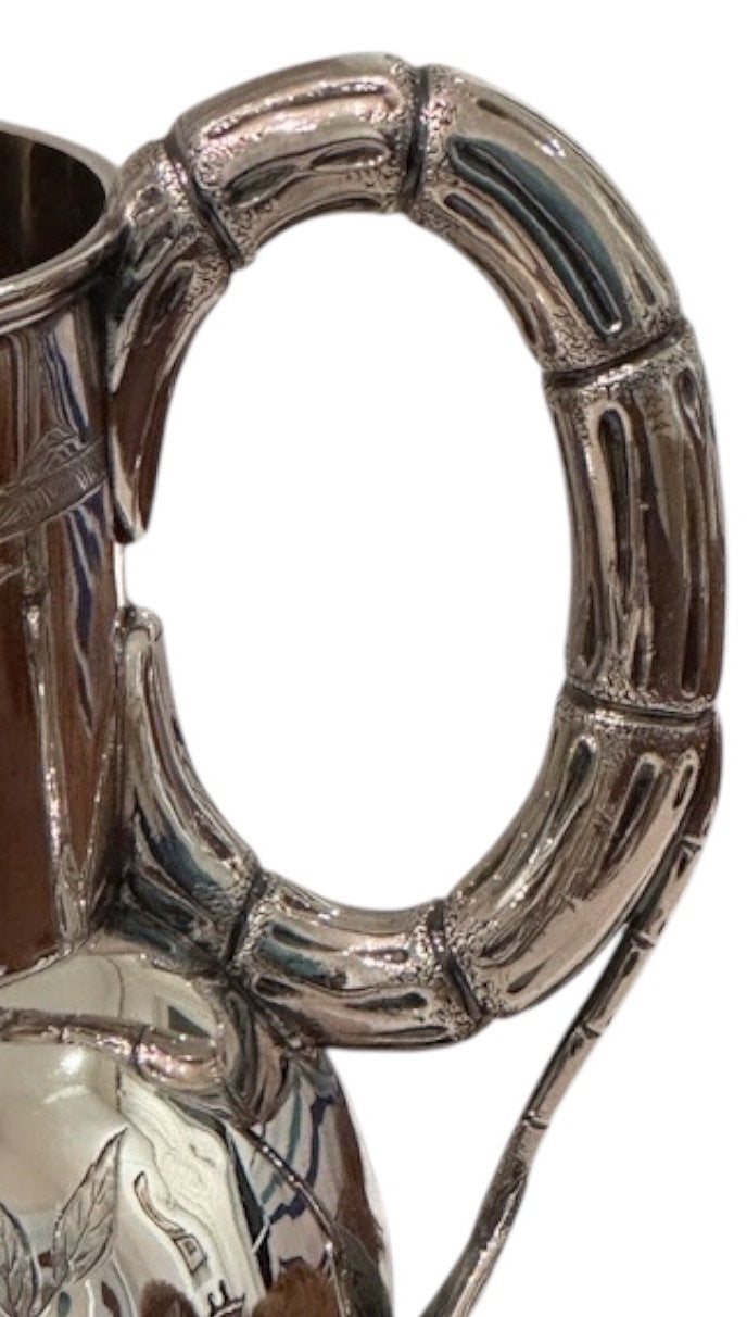 Close-up of the silver pitcher's bamboo-form looped handle with segmented joints