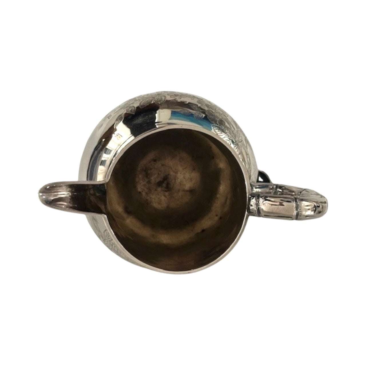 Top-down view into the silver pitcher's mouth showing interior and handle
