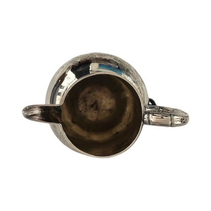 Top-down view into the silver pitcher's mouth showing interior and handle
