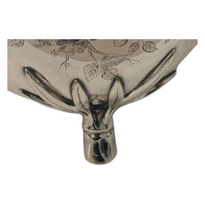Close-up of the silver pitcher's bamboo-style foot beneath the engraved lower body