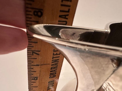 Close-up of the silver pitcher's pouring spout beside a measuring ruler