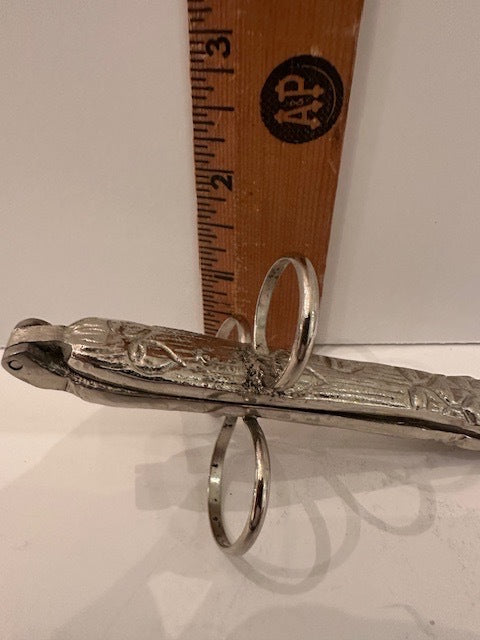 Hinged asparagus utensil beside a wooden ruler showing about three inches