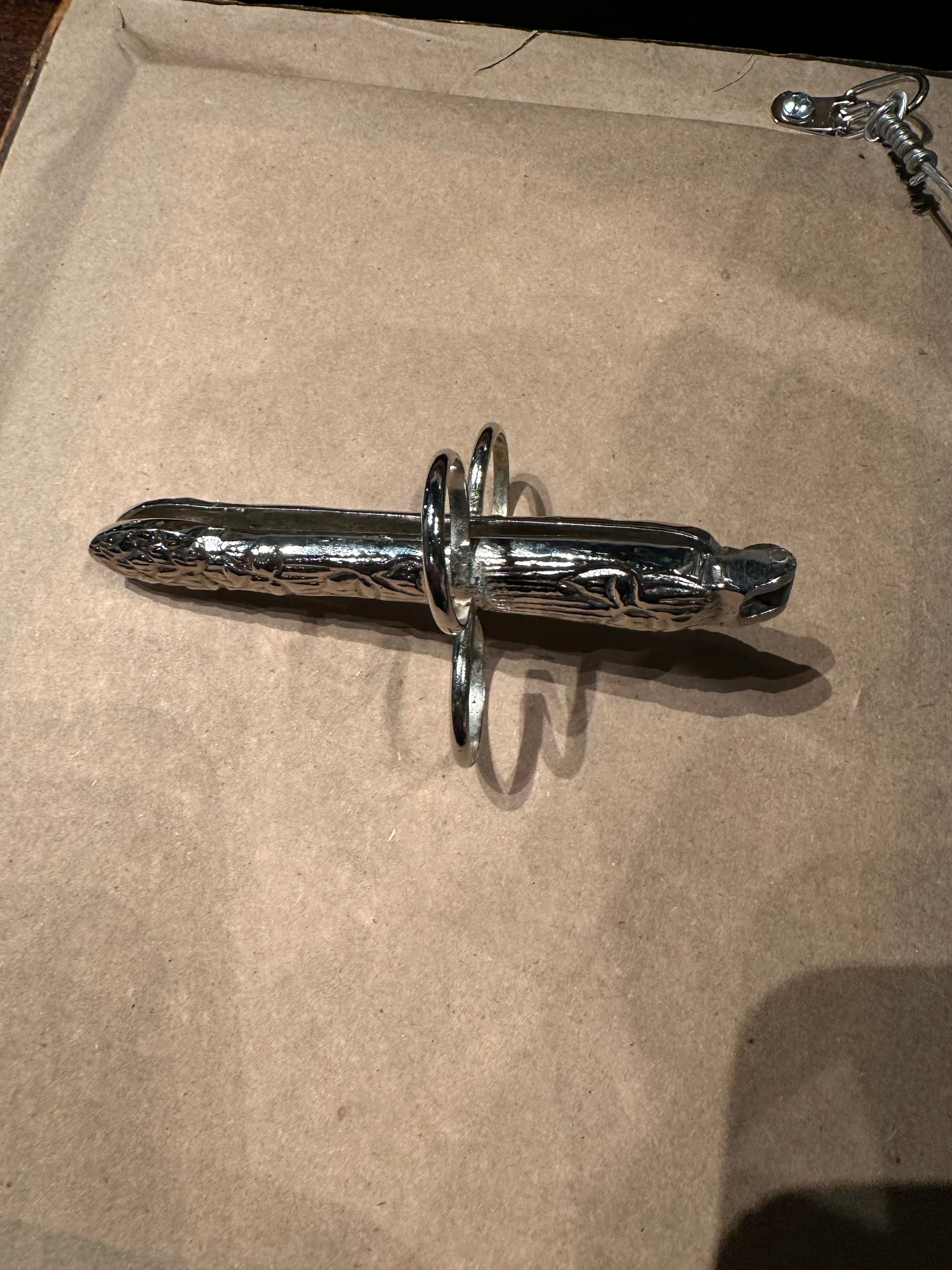 Side view of a hinged silver plate asparagus utensil with finger loops
