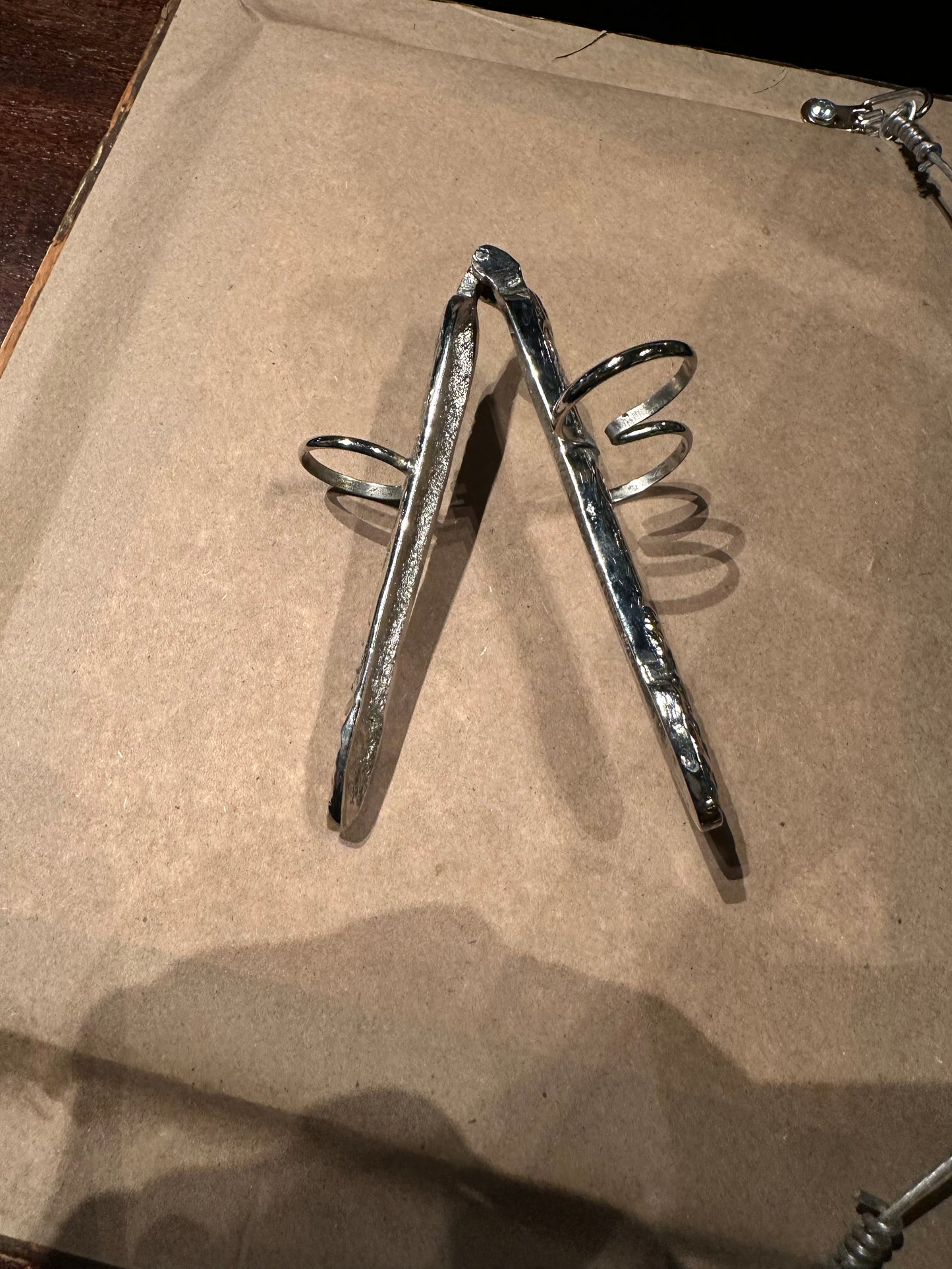 Asparagus utensil opened on its hinge into a V, showing both arms and finger loops
