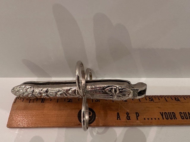 Silver plate asparagus utensil beside a ruler spanning roughly five inches